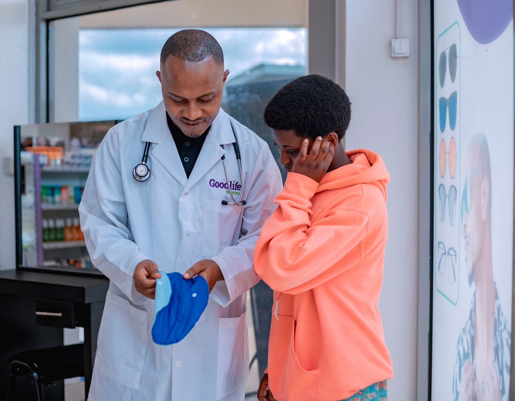 A pharmacist showing a reusable menstrual pad to a teenage girl.